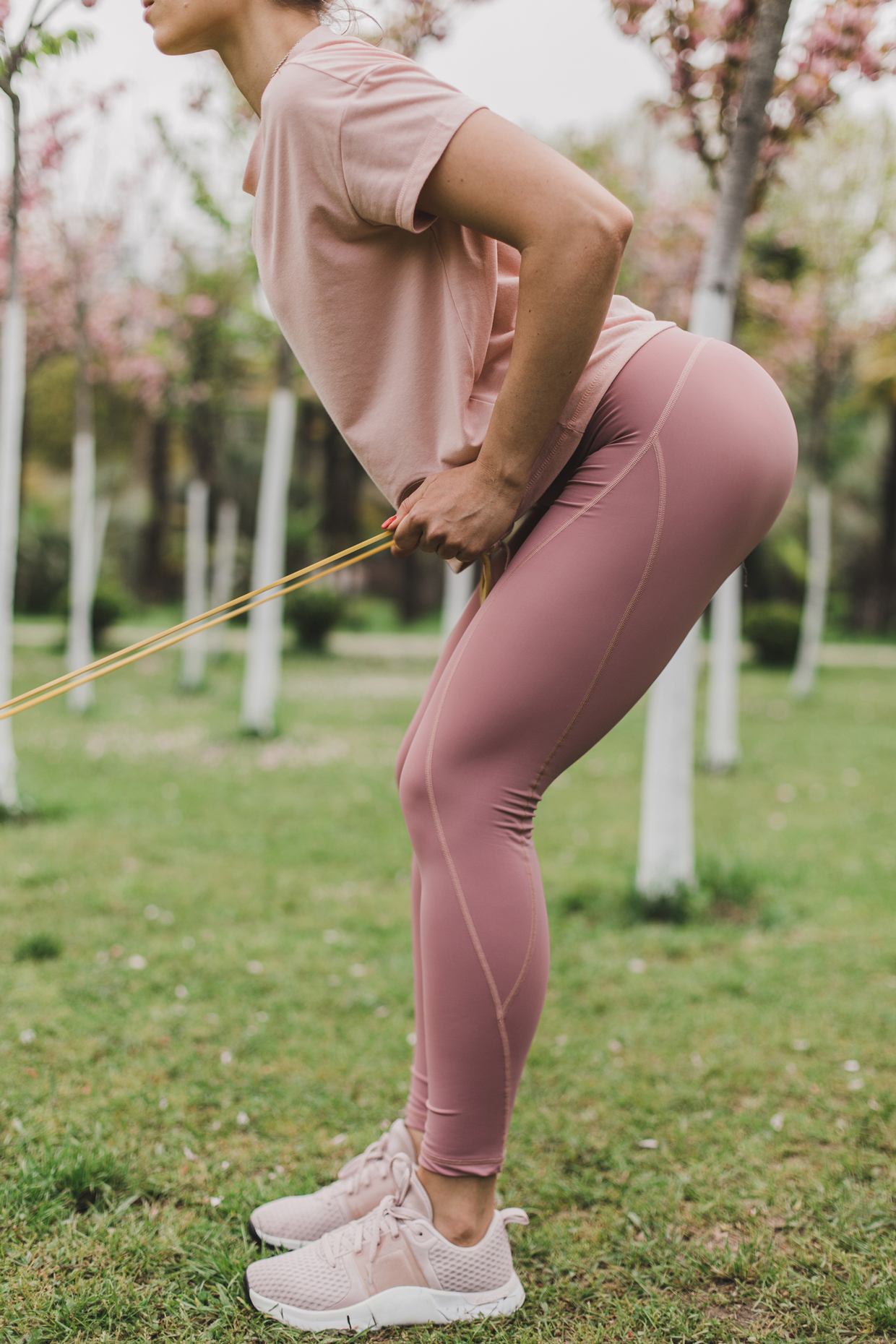 woman pink leggings and a T-shirt is engaged in outdoor sports among flowering trees