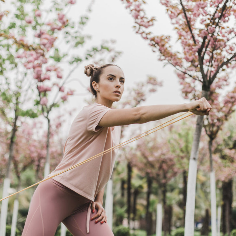 woman pink leggings and a T-shirt is engaged in outdoor sports among flowering trees