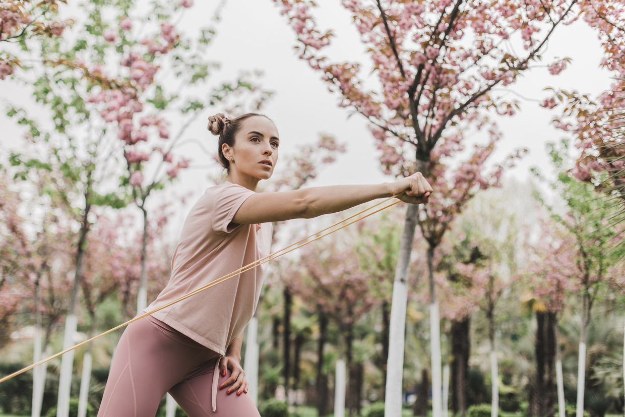 woman pink leggings and a T-shirt is engaged in outdoor sports among flowering trees