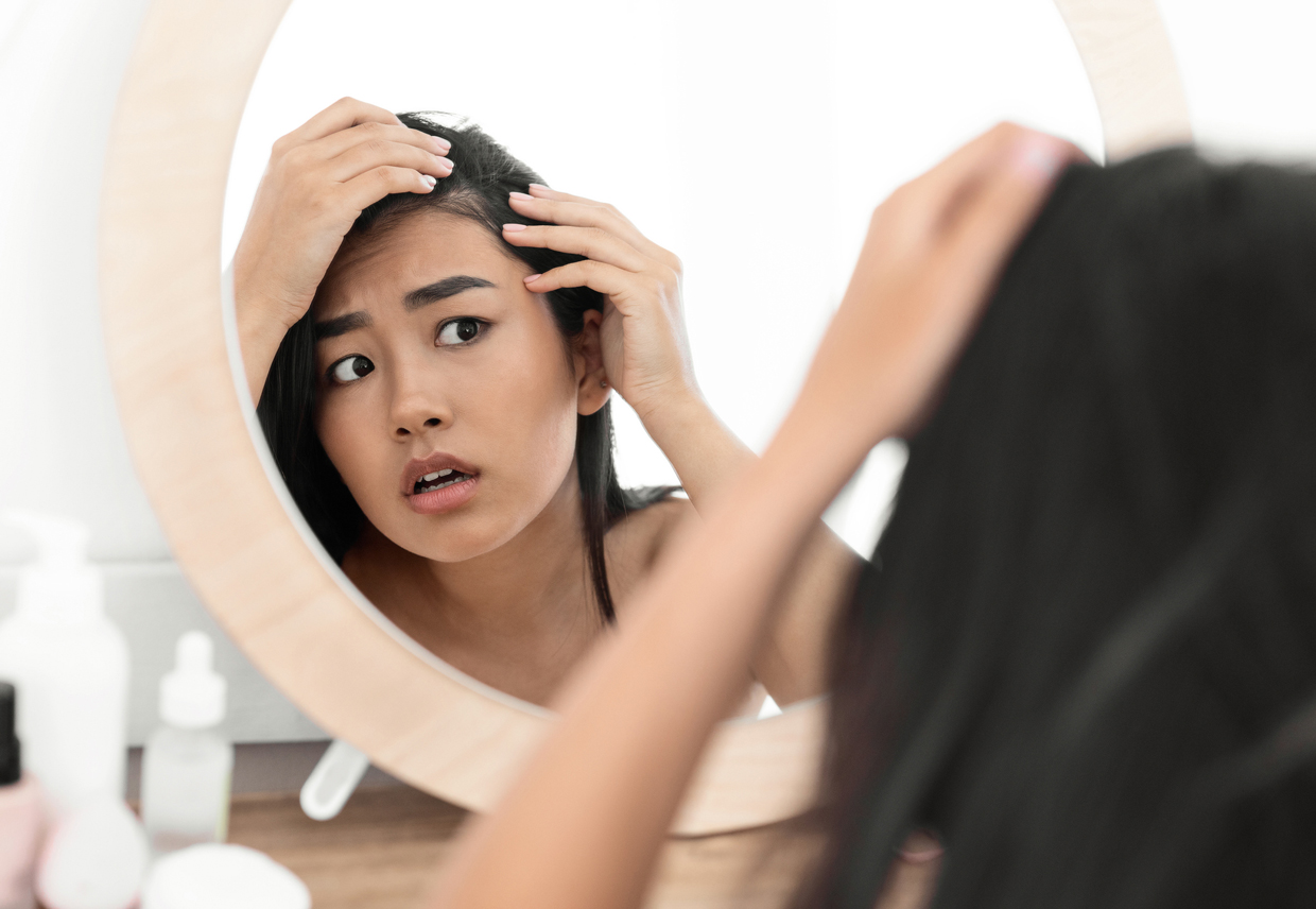 woman checking her hair in mirror at home