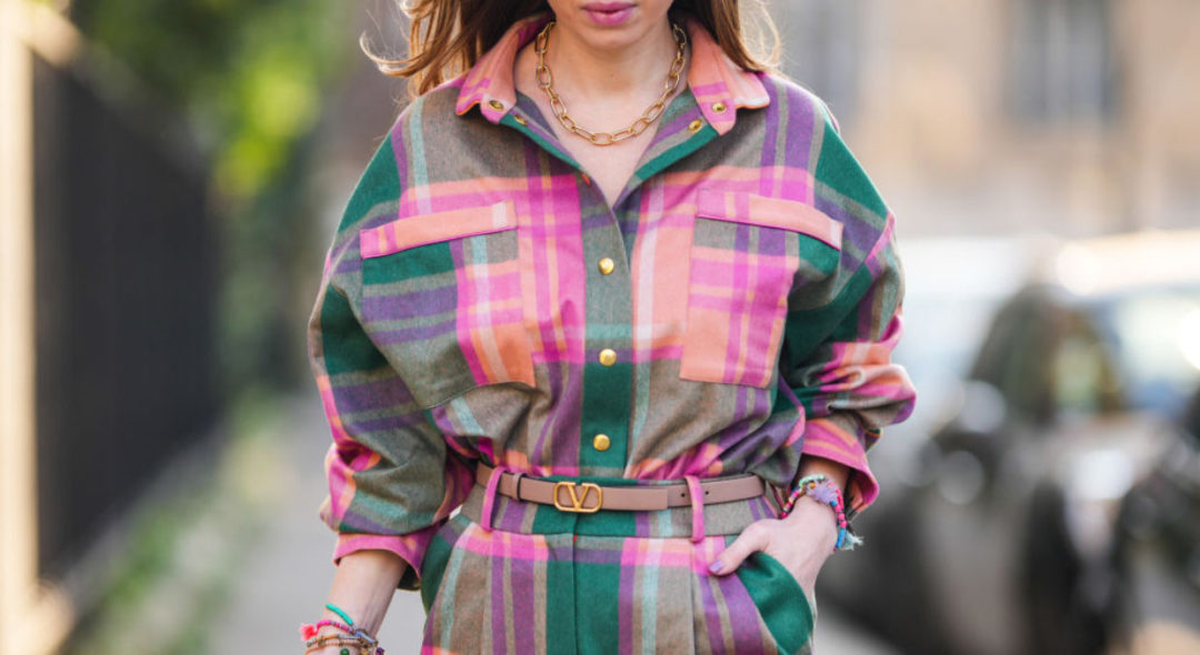 woman wearing a checkerboard pink shirt and pants walking on the street
