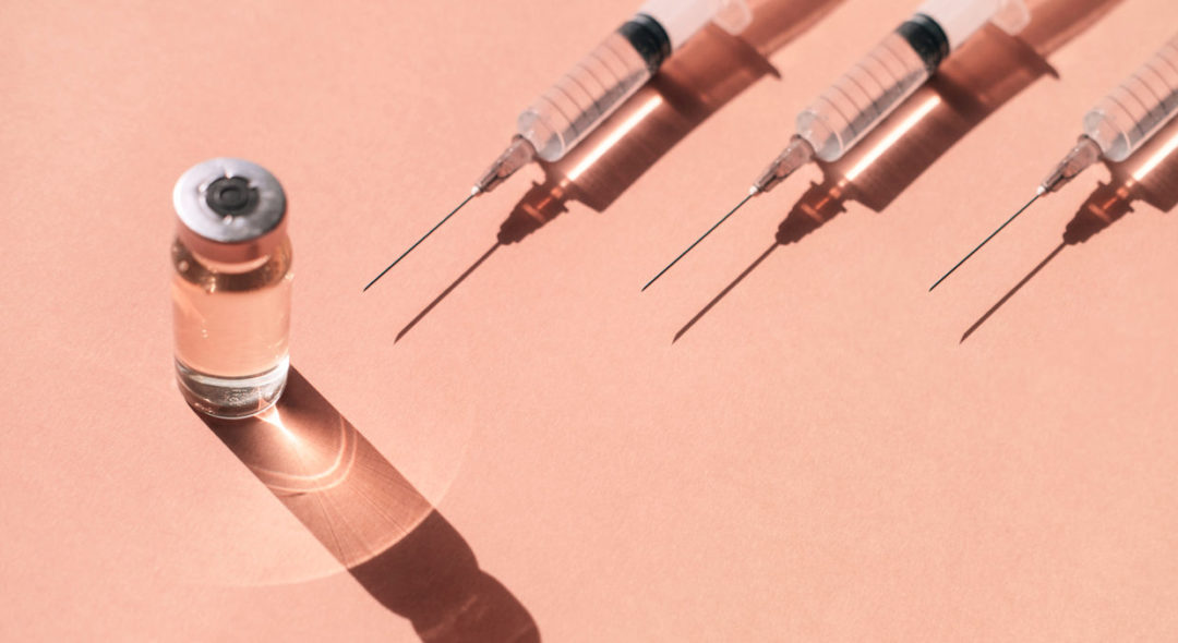 syringe placed on pastel peach orange background with shadows