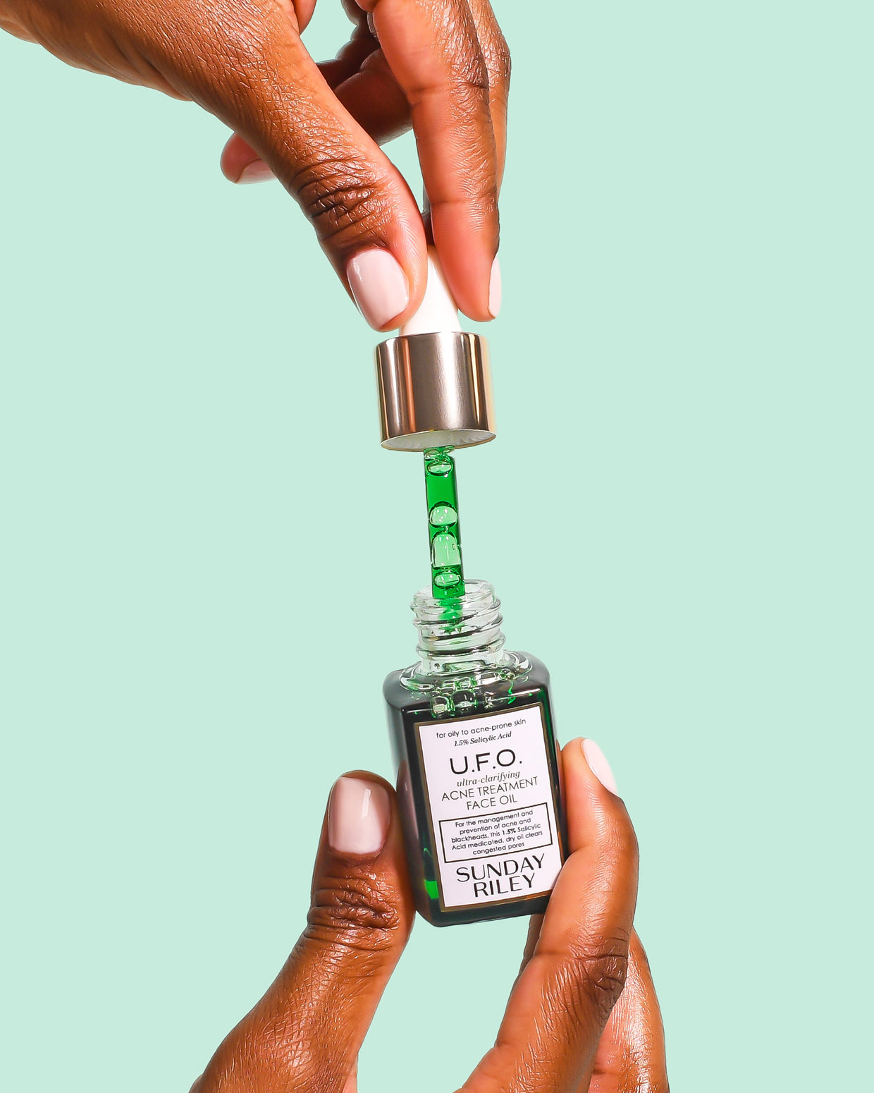 hand holding UFO serum on color background