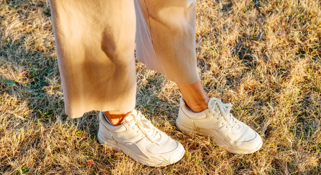 woman walking in grass wearing sneakers