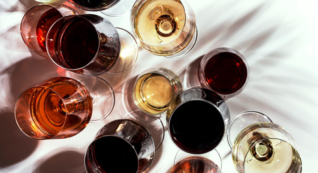 Red, white, rose wines in glasses in assortment on white background, top view