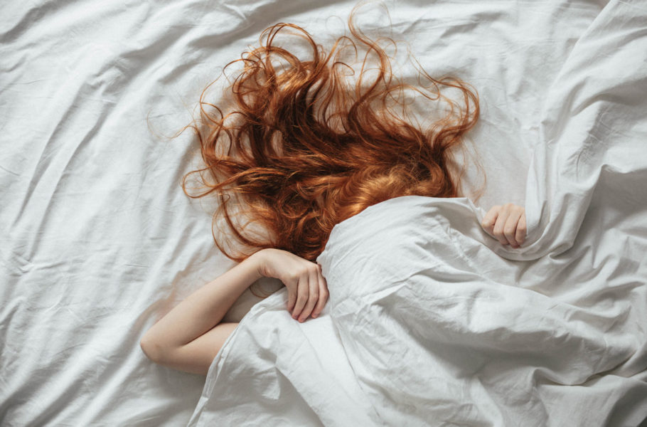 woman pulling bed covers on her face