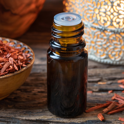 A bottle of sandalwood essential oil with red sandalwood chips