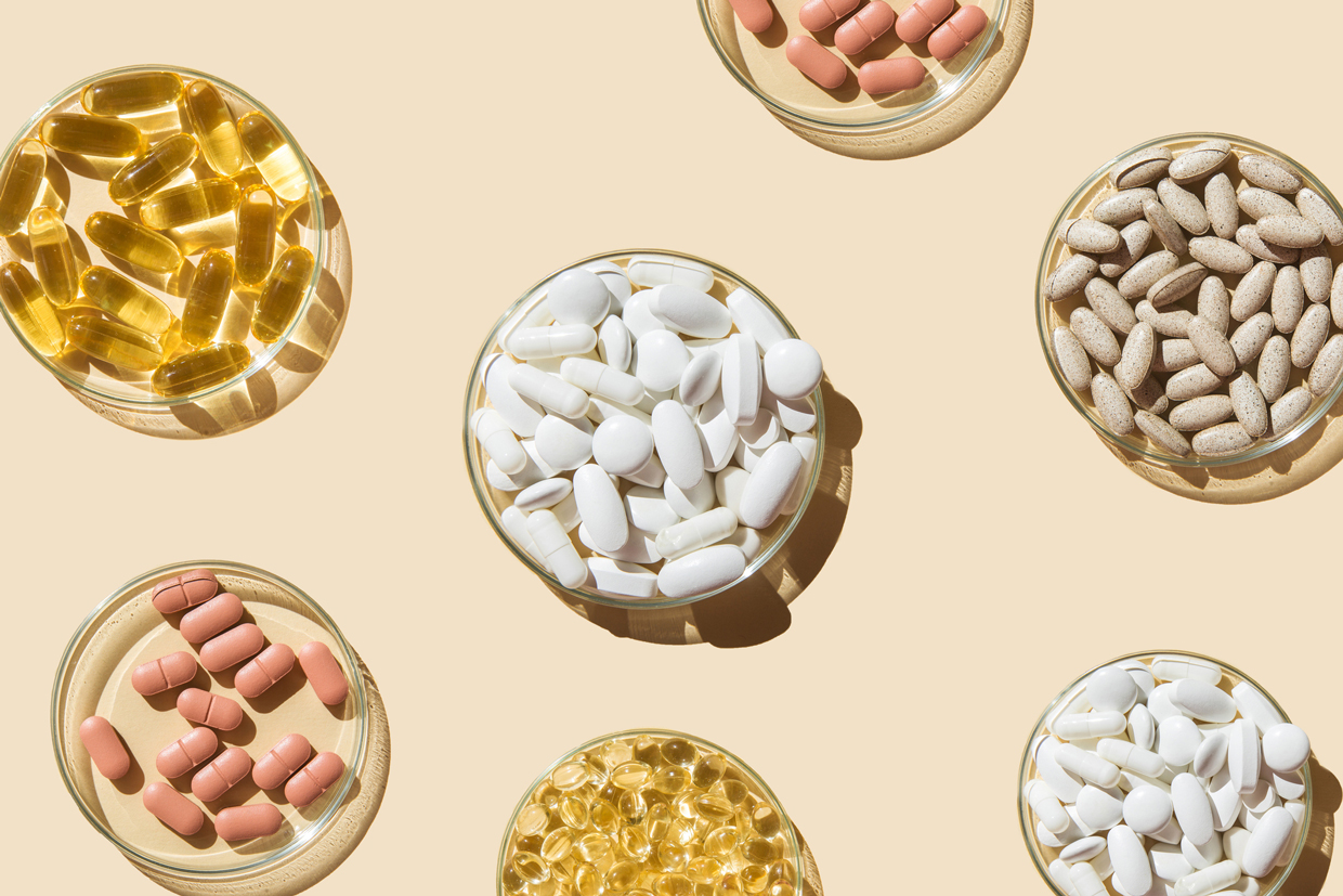 Various pills and capsules, vitamins and dietary supplements in petri dishes on a beige background