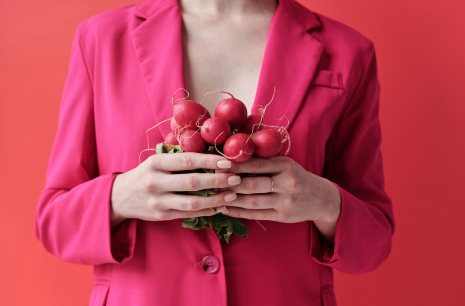 woman in a pink blazer holding radishes
