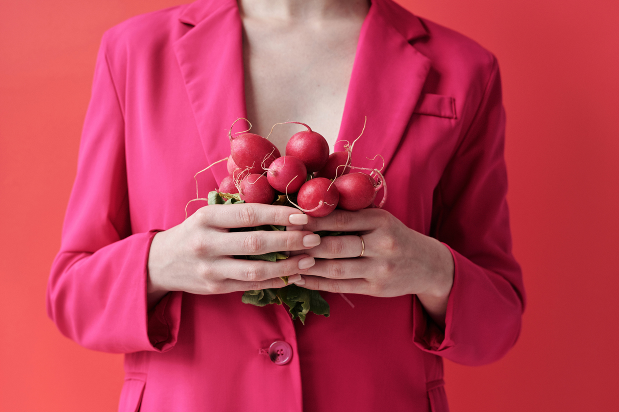 woman in a pink blazer holding radishes