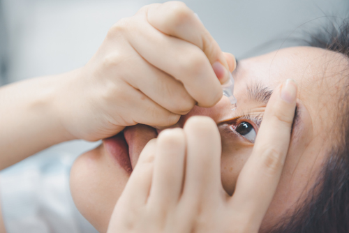 woman holding eye drops