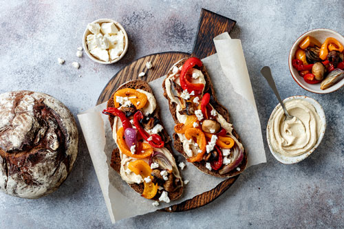 Roasted vegetables toast with hummus and feta cheese on sourdough bread
