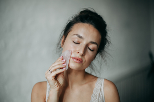 woman placing gua sha in her face