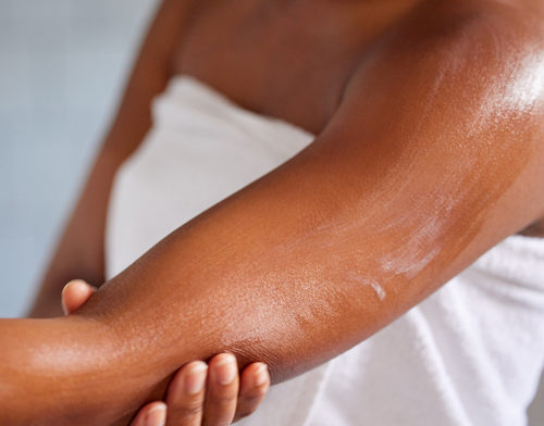 Shot of a woman massaging lotion into her skin