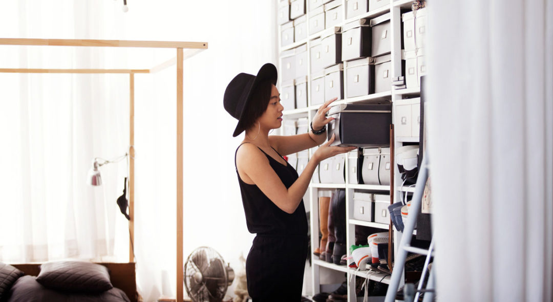 Woman searching in box by shelves in bedroom