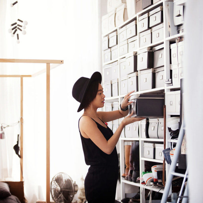 Woman searching in box by shelves in bedroom