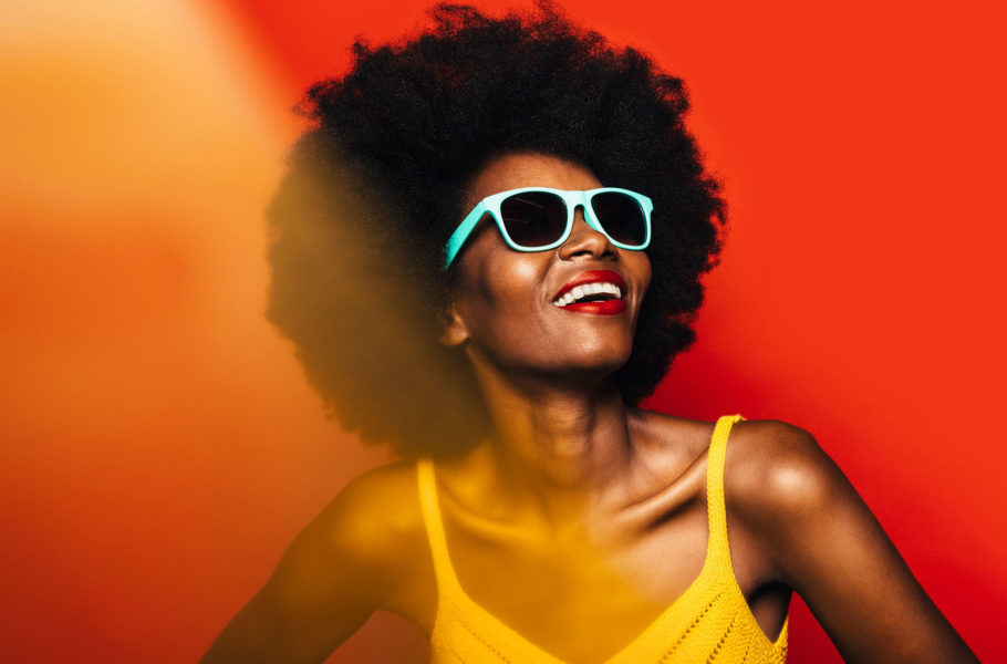 Woman posing over yellow background with blue sunglasses