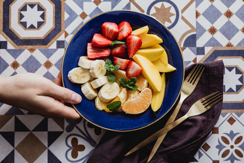 Hand holding fruit bowl on tile table