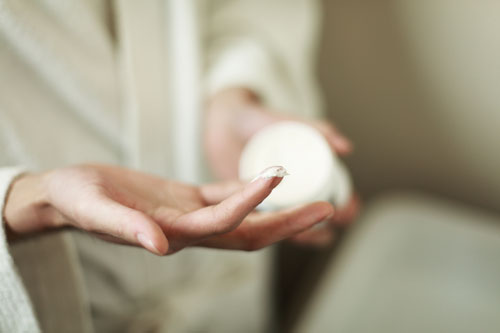 hand with skincare lotion on finger