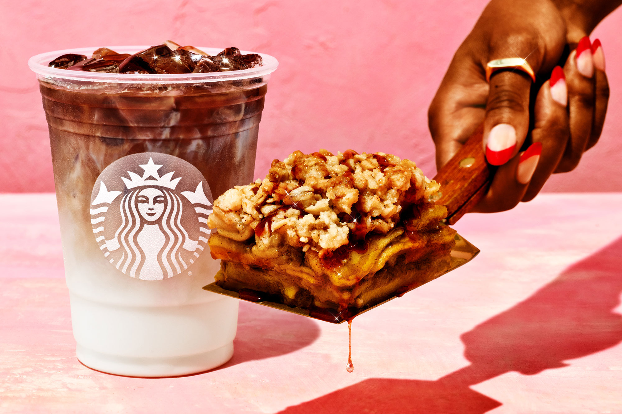 hand holding Starbucks pastry and iced beverages