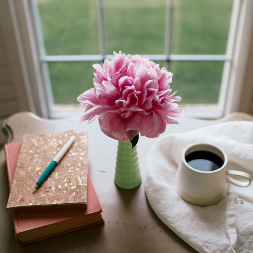 Journal, book, coffee, and flower on a desk