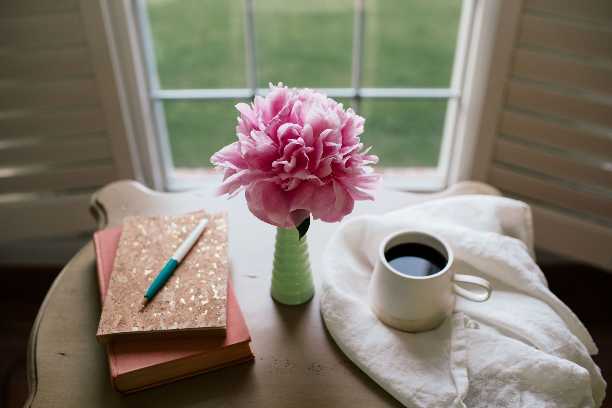 Journal, book, coffee, and flower on a desk