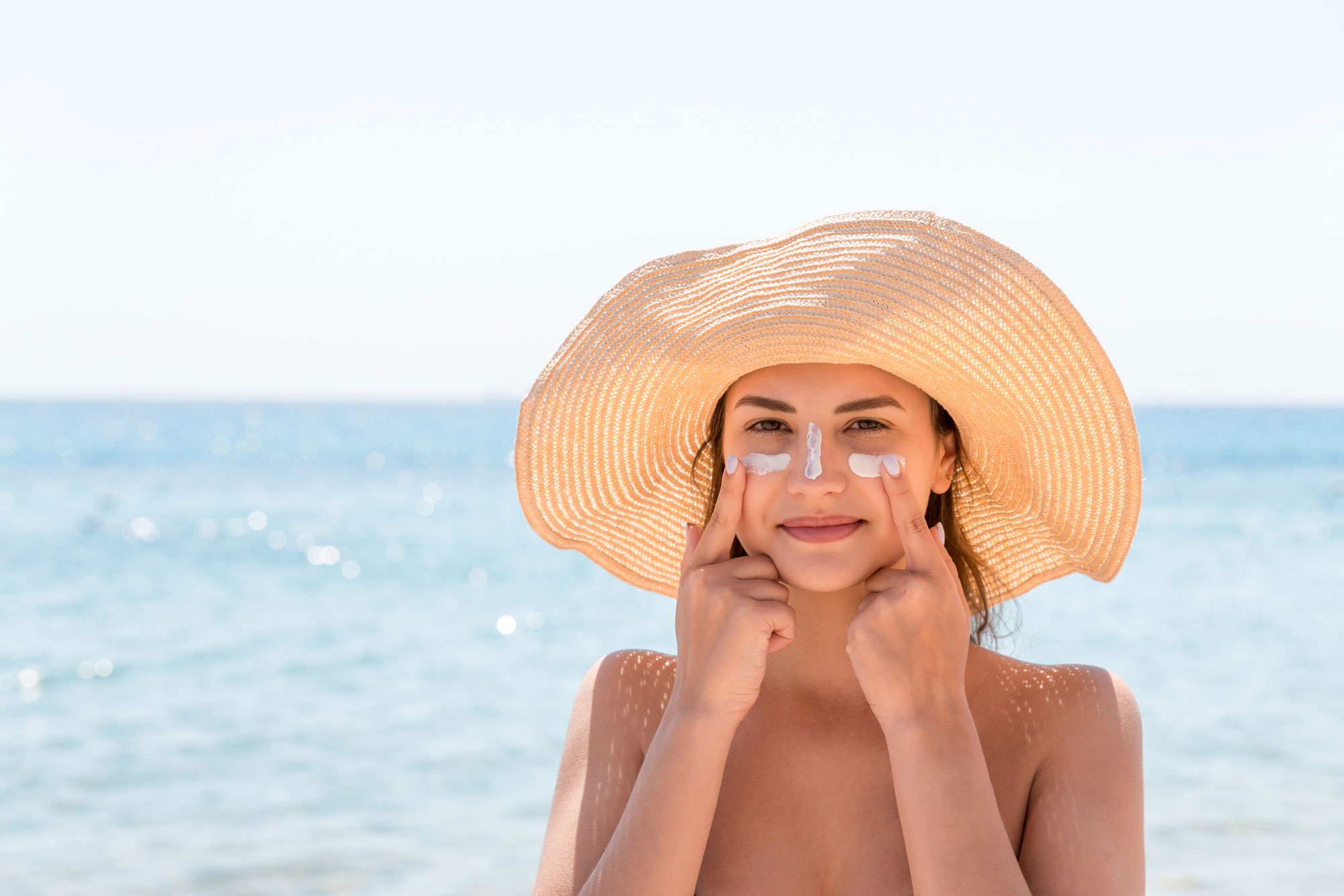 woman protects her skin on face with sunblock at the beach