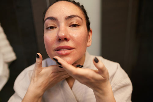 Woman smearing lotion on neck