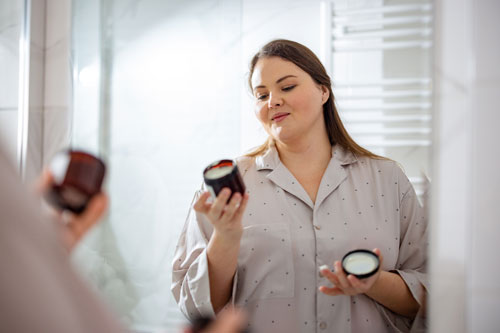 Woman Reading the Label of a Face Cream in her Bathroom