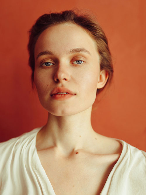 portrait of woman posing against terracotta wall.