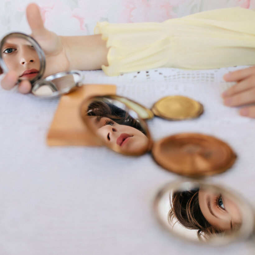 young woman looking at compact mirrors on table