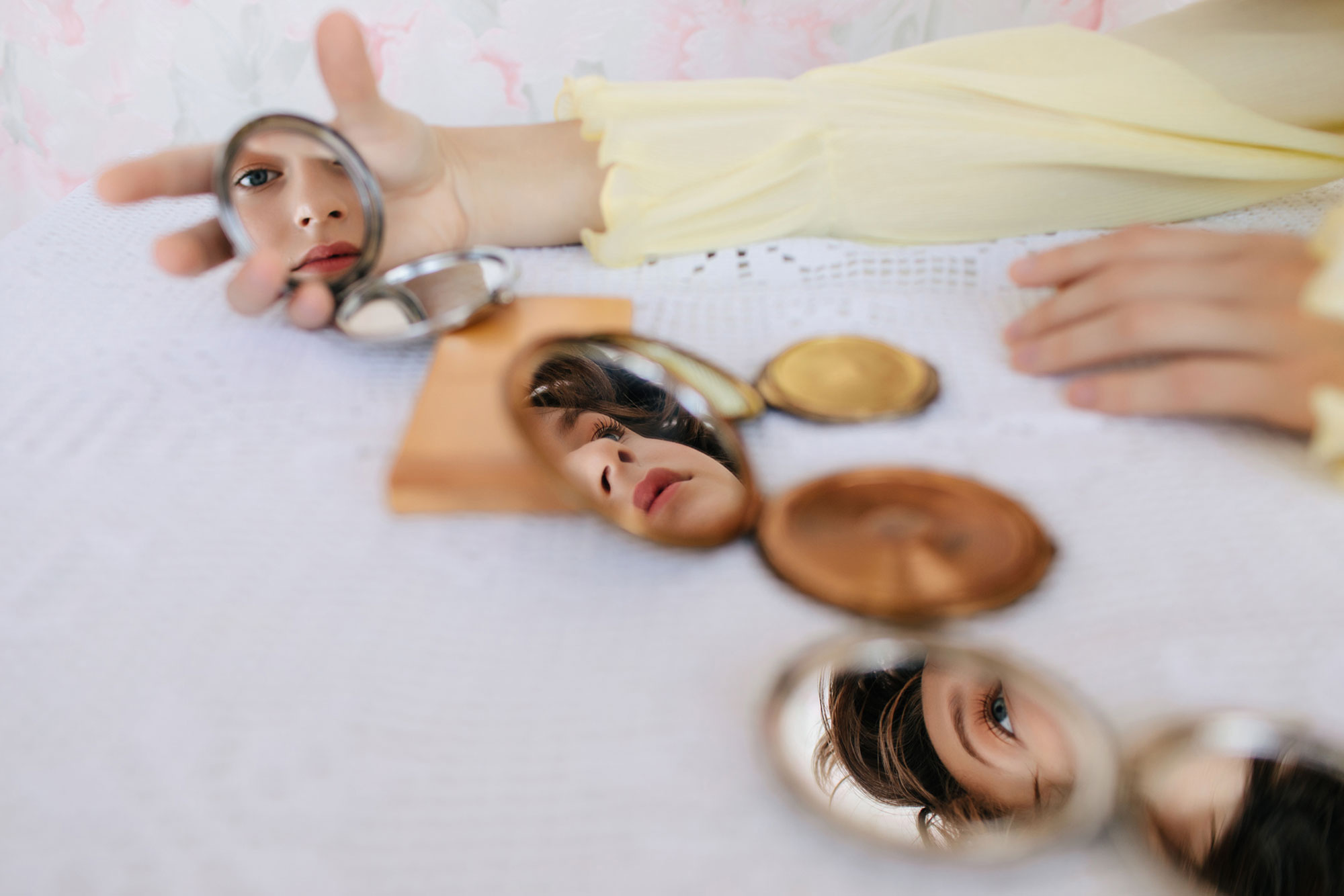 young woman looking at compact mirrors on table
