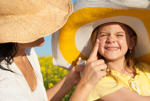 Mother rubbing sunscreen on daughter