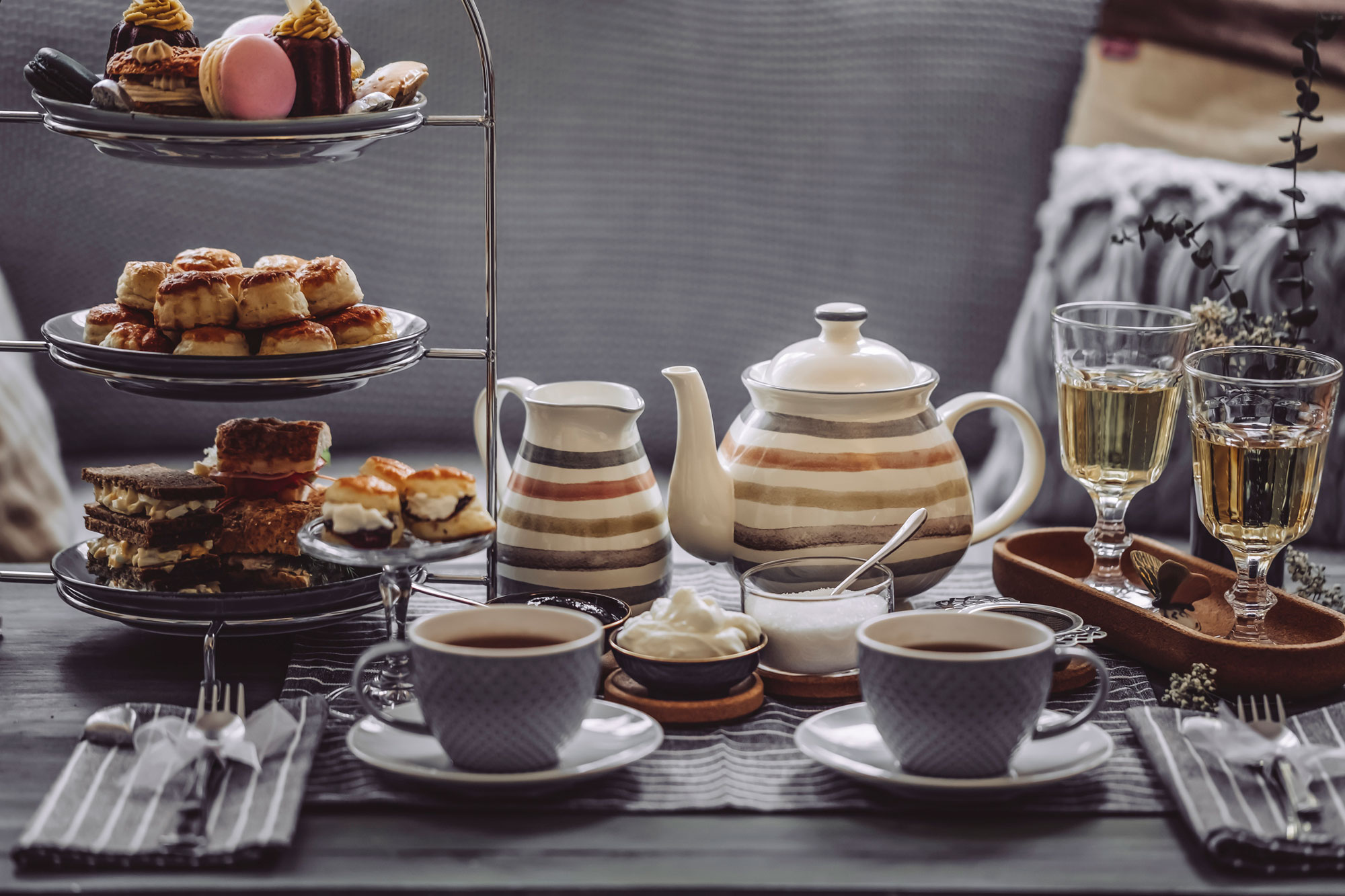 still life shot of table set up for a tea party with tea kettle, cups and small bites
