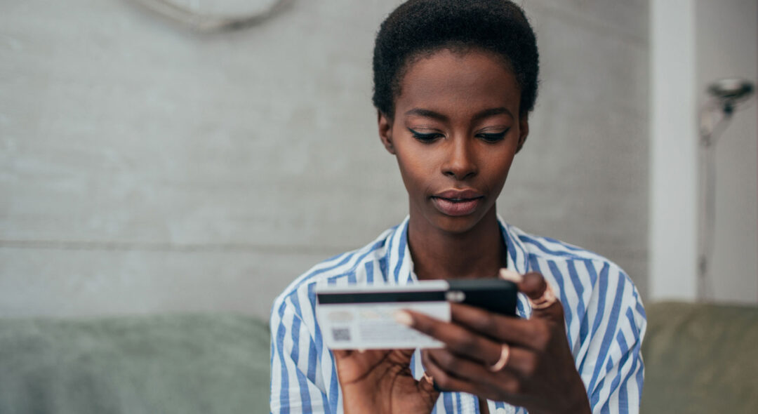 woman holding credit card and cell phone in living room