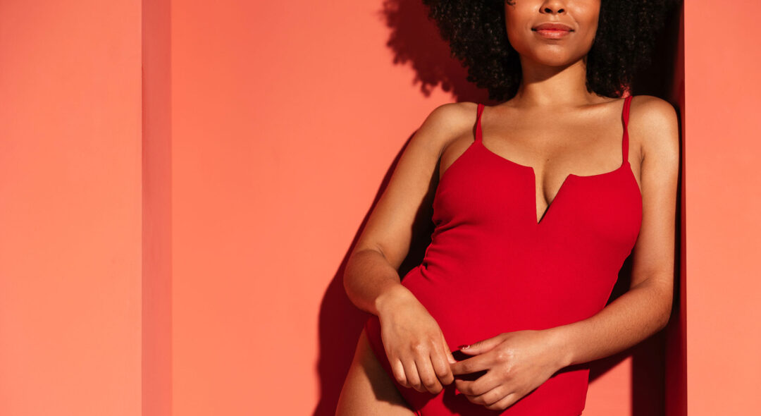 model in red swimwear leaning on wall
