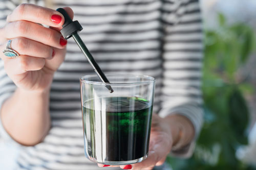woman applying Chlorophyll Supplement to glass of water