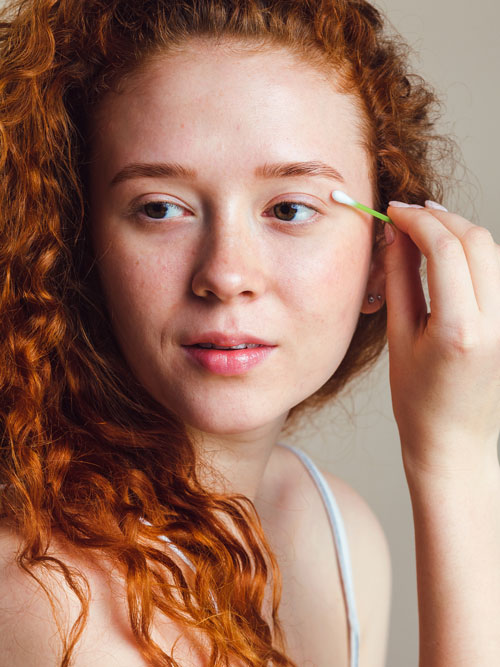 girl in studio placing q-tip on face