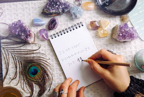 Top view of woman hands doing math on table with crystals