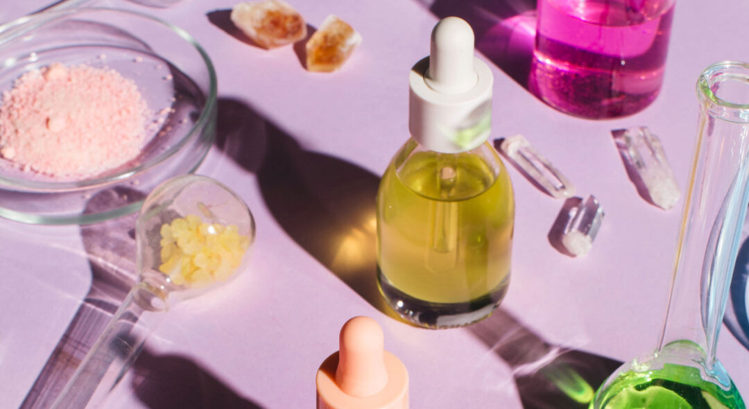 Colorful background with laboratory utensils, samples of cosmetics and glass vials on a purple background