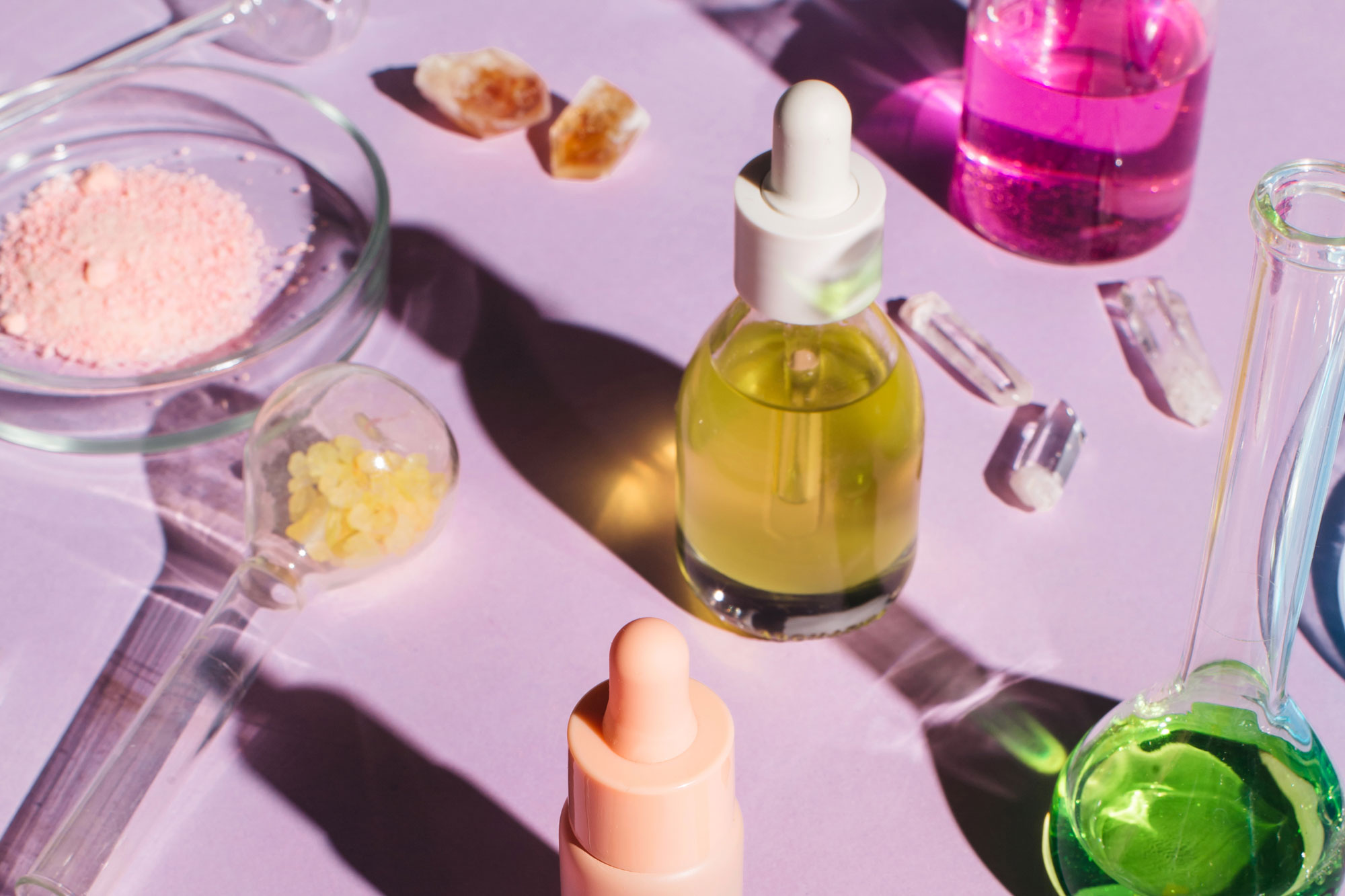 Colorful background with laboratory utensils, samples of cosmetics and glass vials on a purple background