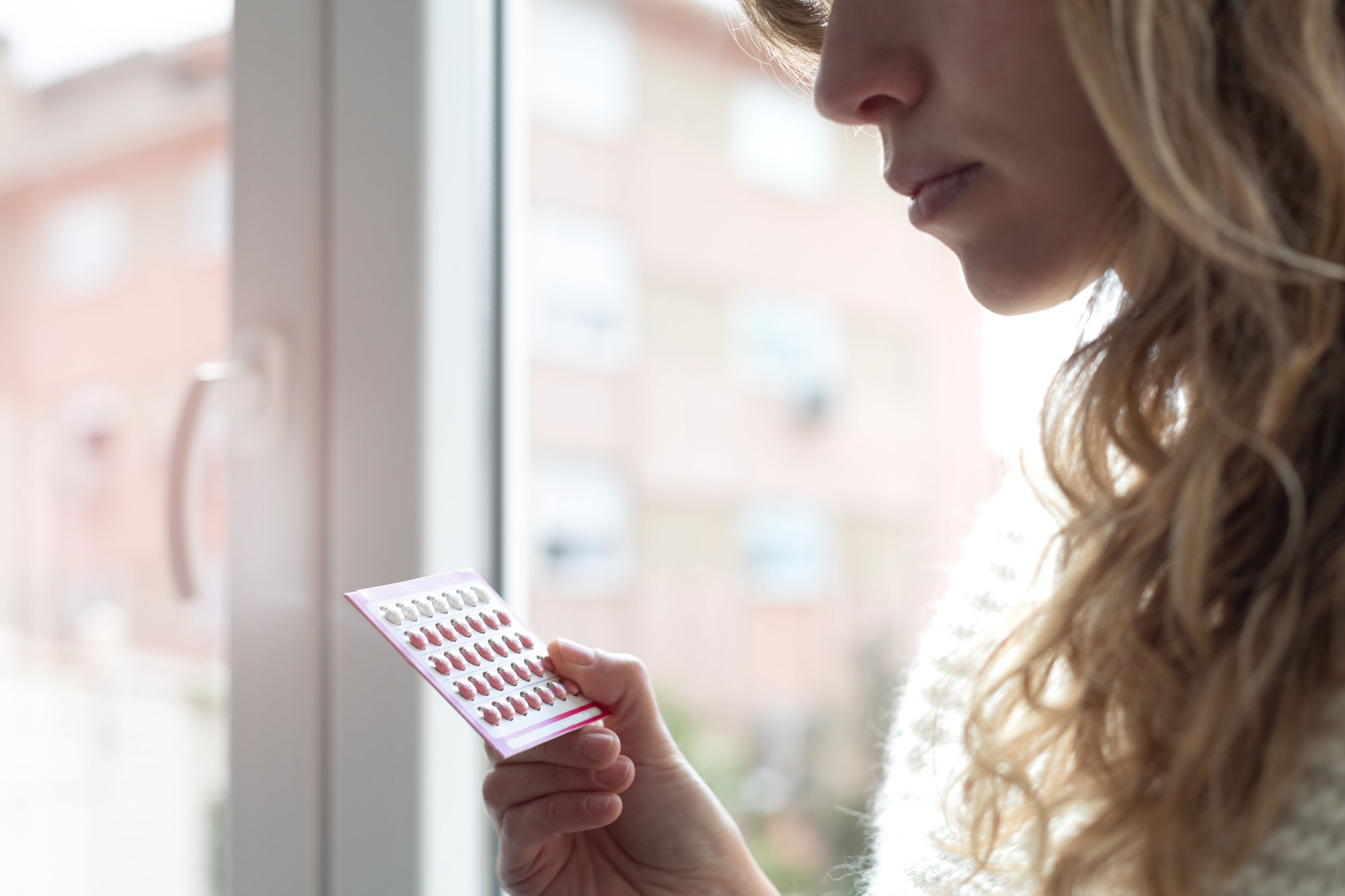 woman holding contraceptive pills at home