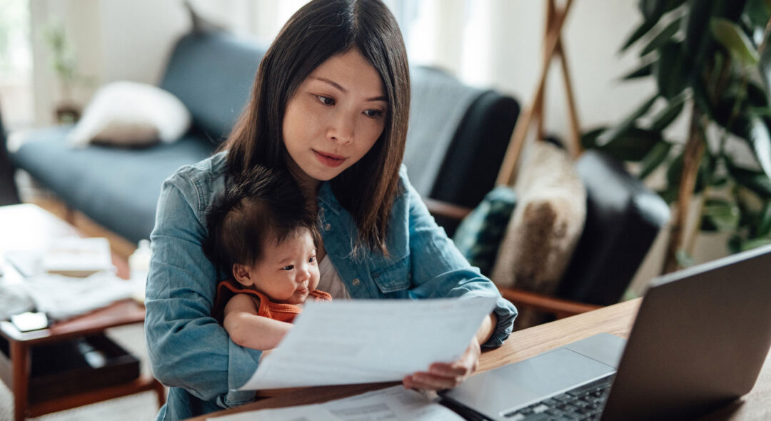 mother with baby daughter working on her laptop from home