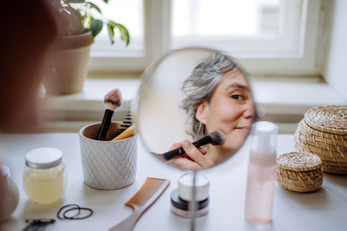 woman applying a make up at home in front of mirror