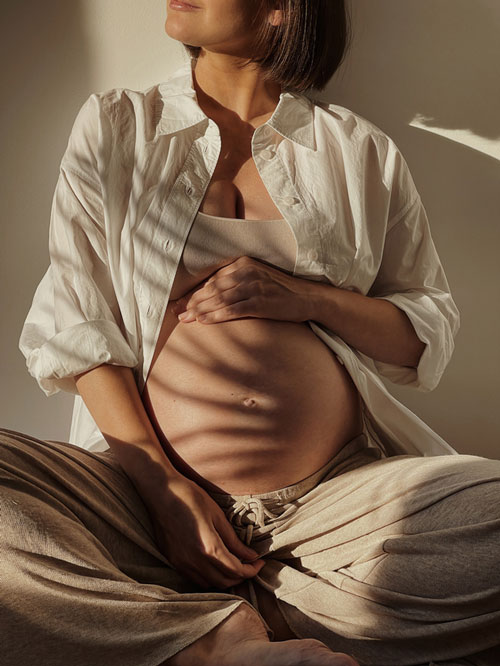 pregnant woman holding belly in natural light