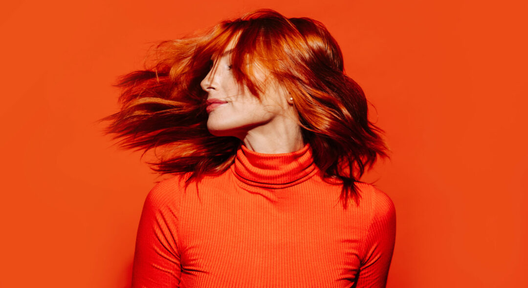 portrait of woman with red hair on orange background