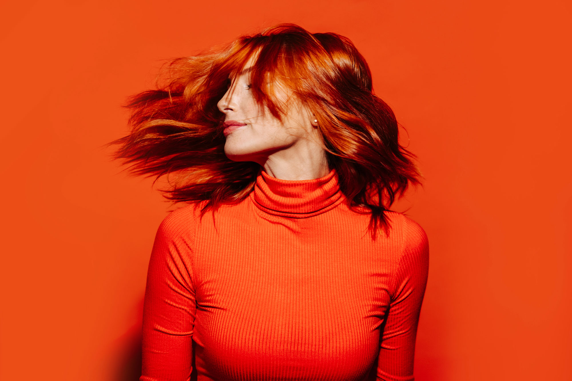 portrait of woman with red hair on orange background