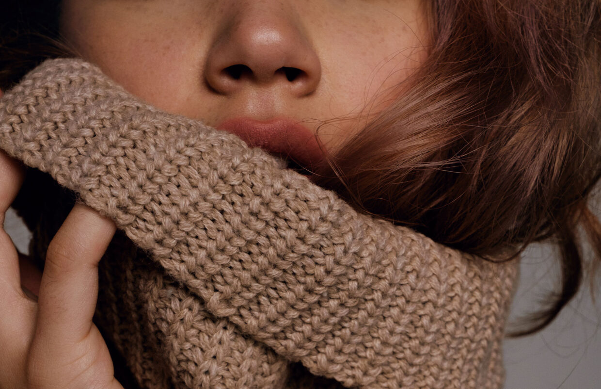 Woman pulling sweater collar up on lips