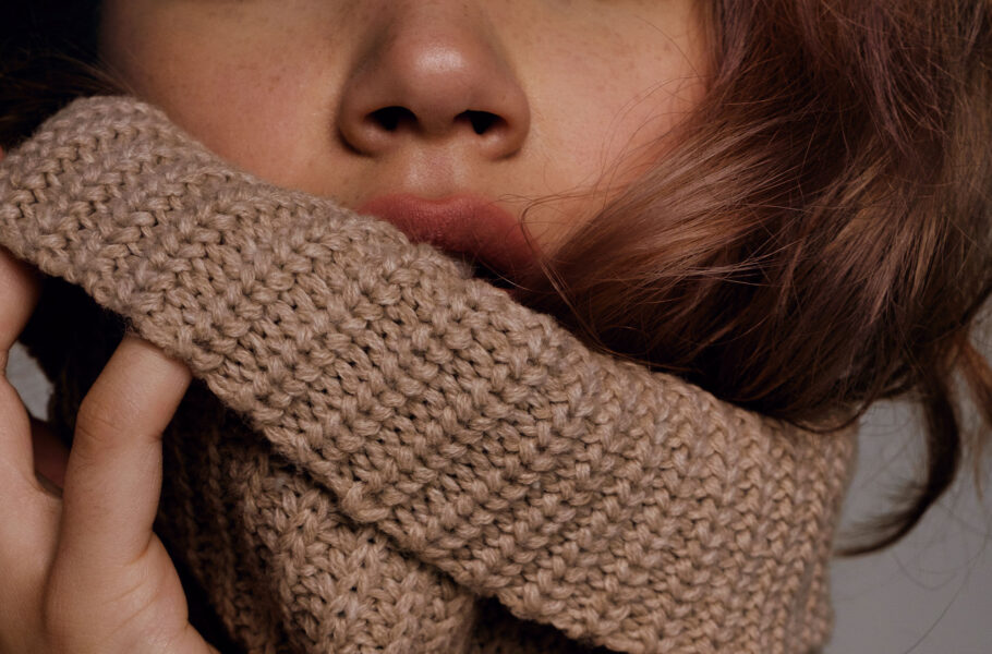 Woman pulling sweater collar up on lips