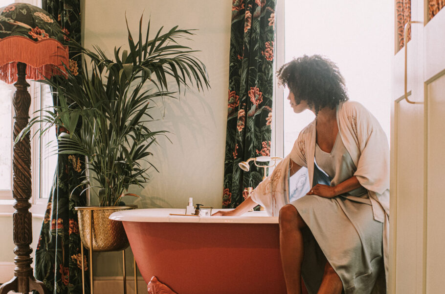 woman wearing a silk robe perching on the side of a roll top bathtub